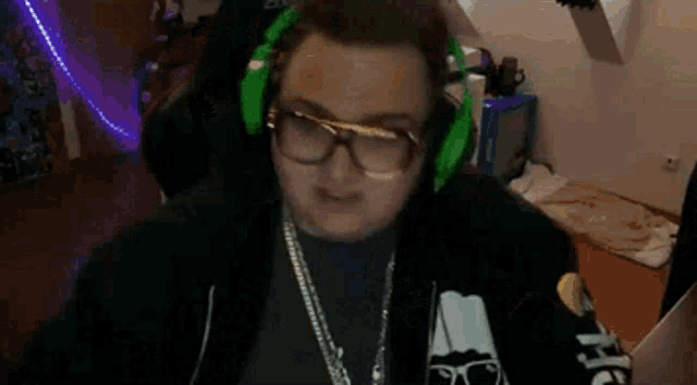 a man wearing glasses and headphones is sitting in front of a computer screen .