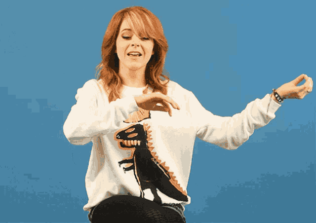 a woman wearing a white sweater with a picture of a dinosaur on it