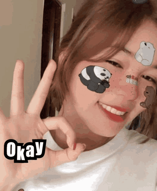 a girl with we bare bears stickers on her face smiles