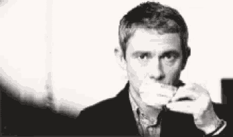 a black and white photo of a man drinking from a cup