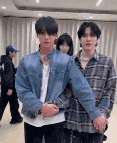 three young men are standing next to each other in a room holding hands .