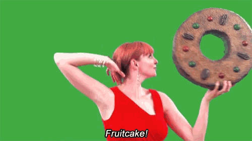 a woman in a red dress is holding a large donut in her hands and says fruitcake