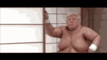 a naked man is standing in front of a window with his arm outstretched .