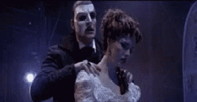 a man in a mask is standing next to a woman in a white dress .