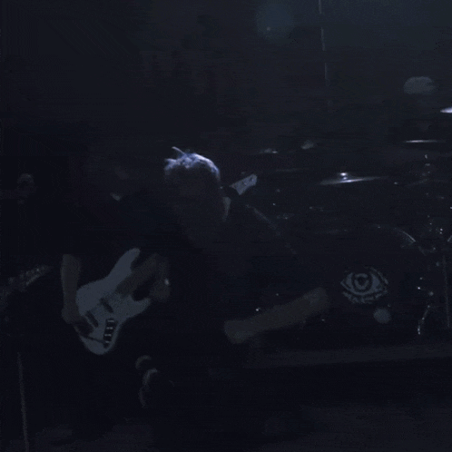 a man playing a guitar in front of a drum set with eyes on them