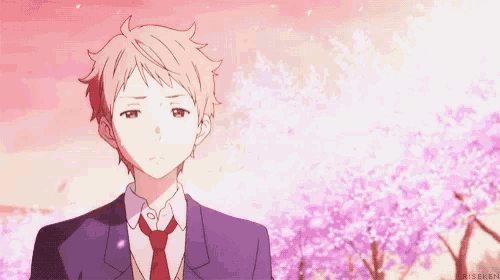 a young man in a suit and tie is standing in front of a cherry blossom tree .