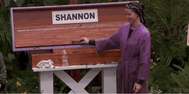 a woman in a purple robe is standing in front of a wooden box that says shannon