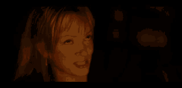a woman with blonde hair is smiling in a dark room