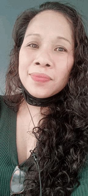 a woman with long curly hair is wearing a black face mask
