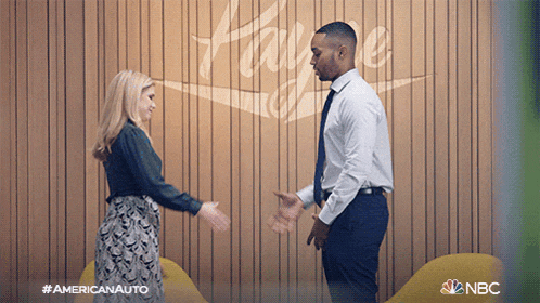a man and woman shake hands in front of a wall that says home