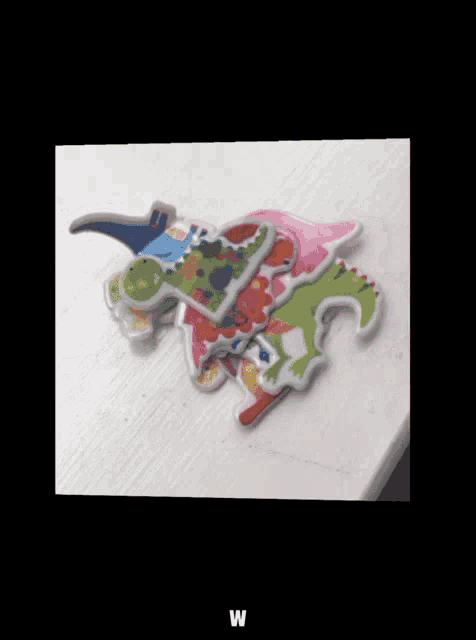 a picture of a stack of colorful dinosaurs with the letter w below them