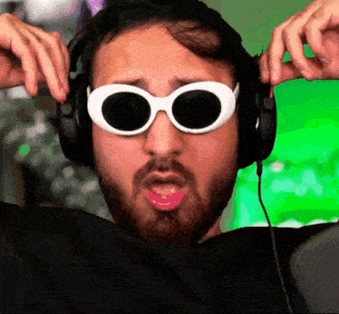 a man wearing headphones and white sunglasses makes a funny face