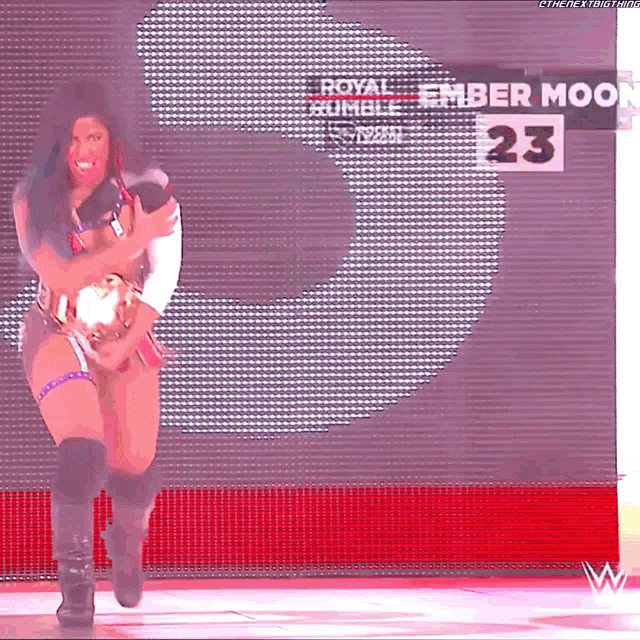 a woman is dancing in front of a large screen that says ember moon 23