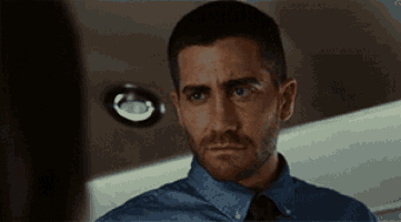 a man with a beard wearing a blue shirt and tie is looking at a woman .