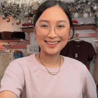 a woman wearing glasses is smiling in front of a sign that says gentil woman