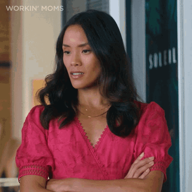 a woman in a pink dress is standing in front of a sign that says workin ' moms
