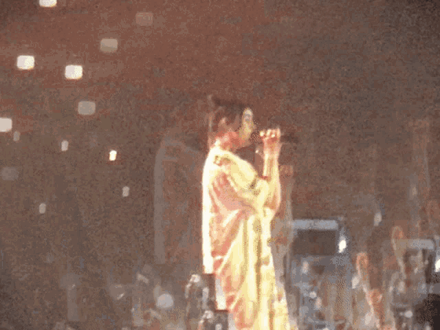 a blurry picture of a woman singing into a microphone in front of a crowd