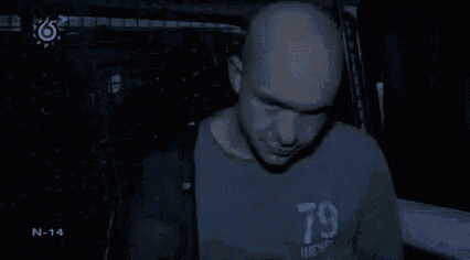 a man in a 79 shirt is standing in a dark room .
