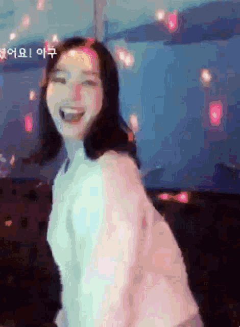 a woman in a pink sweater is smiling with a blue background