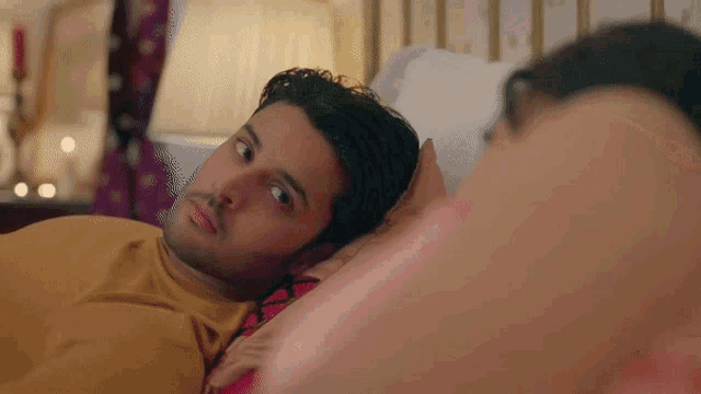 a man laying on a bed looking at another man