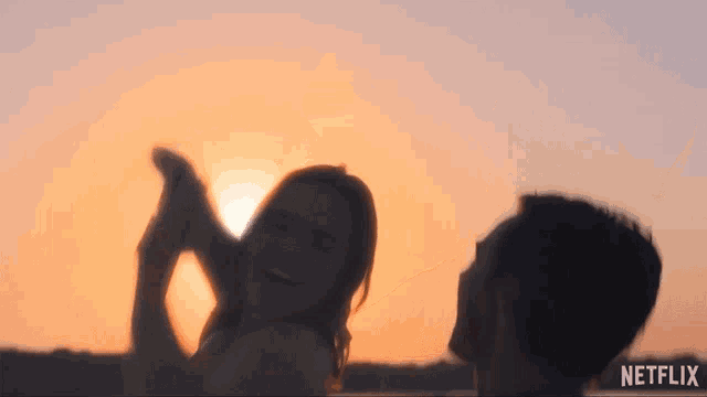 a man and a woman are kissing in front of a sunset with netflix written on the bottom