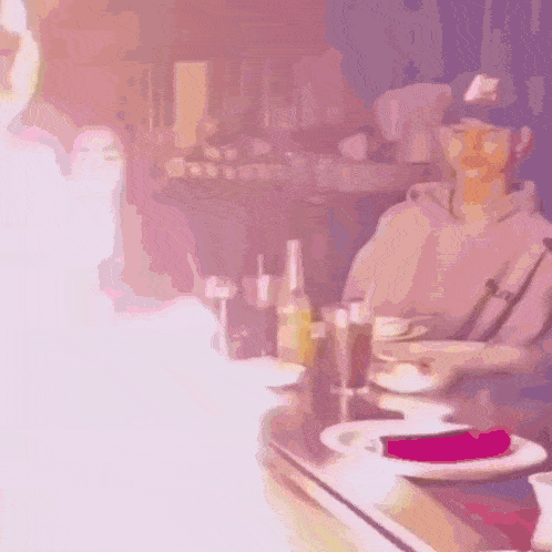 a man is sitting at a table with a plate of food in front of him while flames are coming out of it .
