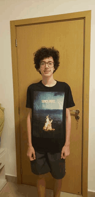 a young man standing in front of a door wearing a black shirt that says sunset nights