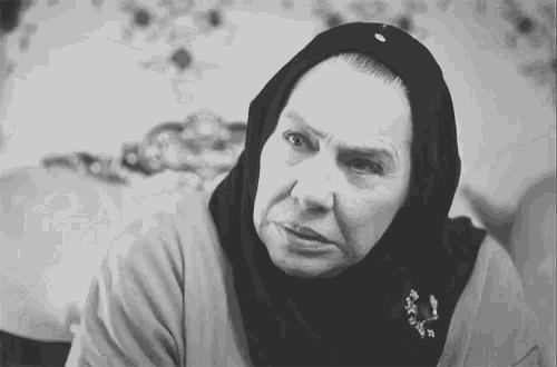 a black and white photo of an elderly woman wearing a head scarf .