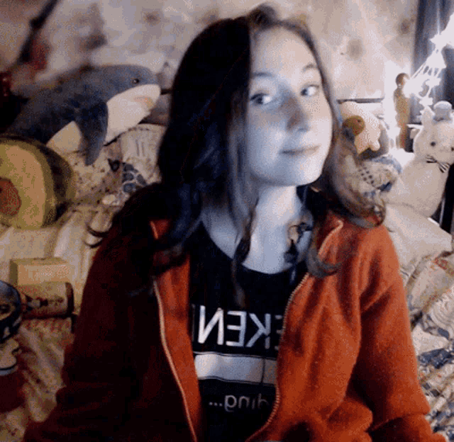a girl wearing an orange jacket and a black shirt that says " eken " on it