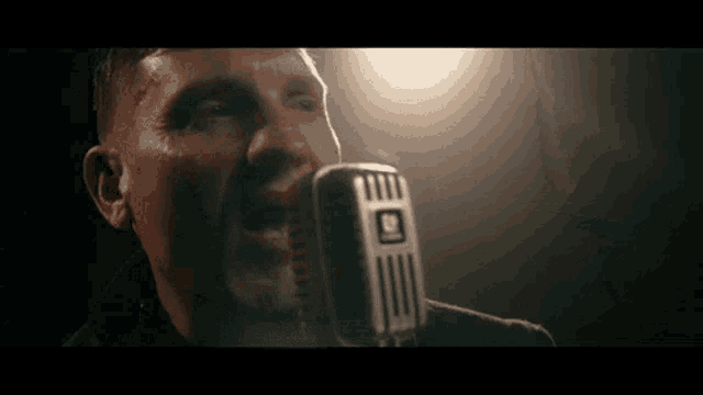 a close up of a man singing into a microphone .