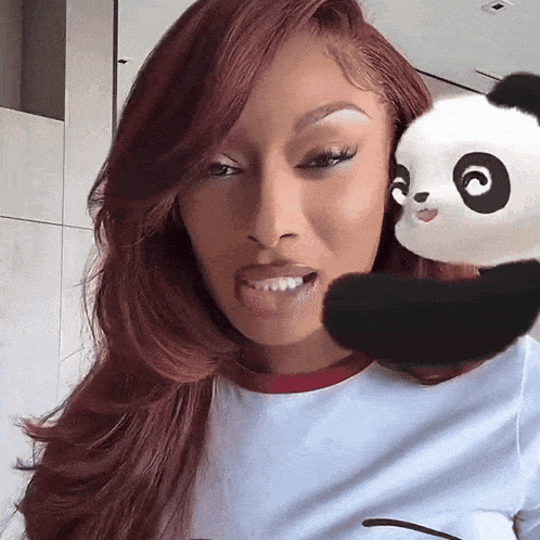 a woman holds a stuffed panda bear in her arms