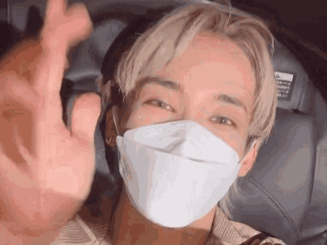 a man wearing a white face mask is making a heart with his hand