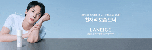 a man leaning on a table with a bottle of laneige in front of him