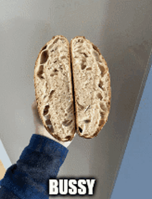 a person is holding a loaf of bread that has been cut in half and has the word bussy on the bottom