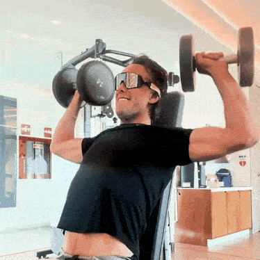 a man lifting a dumbbell in a gym with a sign that says dra on it