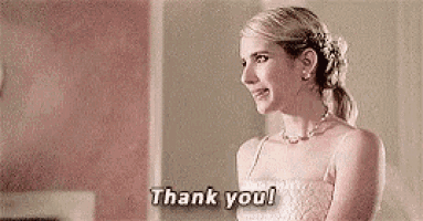 a woman in a white dress is standing in a room and saying `` thank you '' .