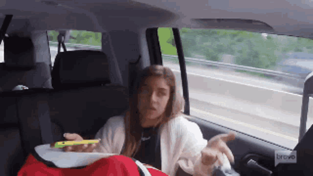 a woman is sitting in the back seat of a car with a bravo logo on the side