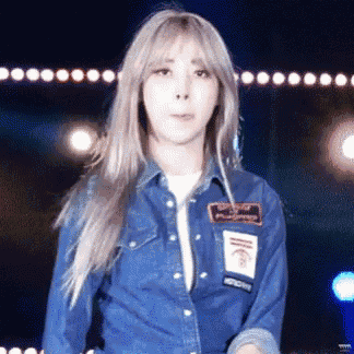 a woman in a denim shirt is standing in front of a stage .