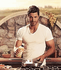 a man in a white t-shirt is cooking in a kitchen
