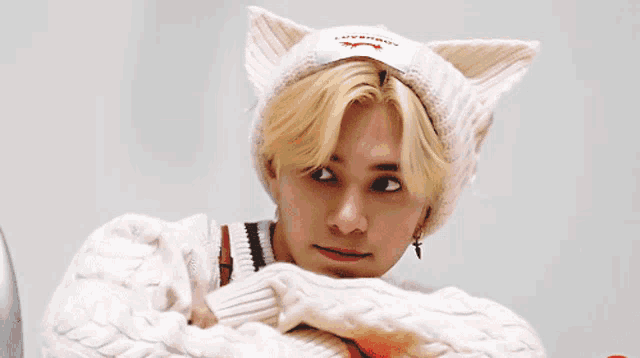 a young man wearing a white cat eared hat