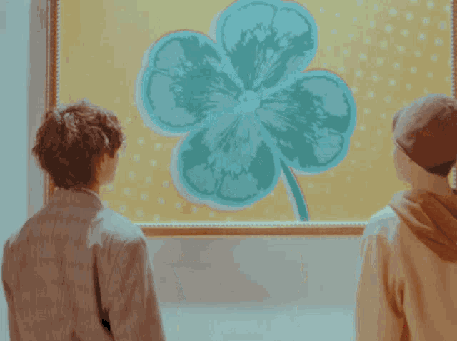 two people are looking at a painting of a clover