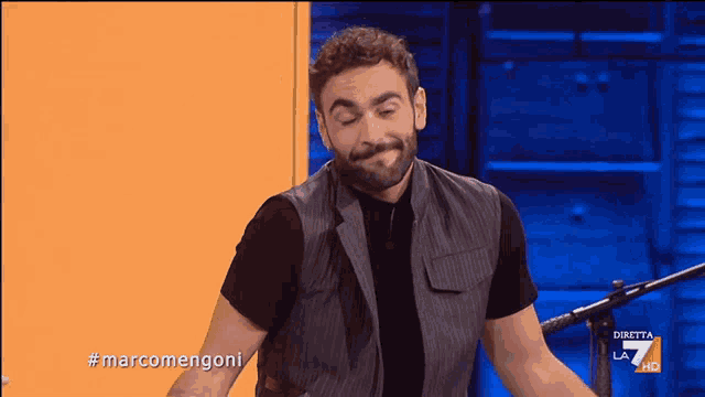 a man with a beard is standing in front of a microphone with the hashtag marcomengoni