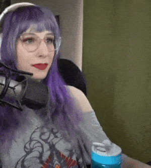 a woman with purple hair is sitting in front of a microphone holding a water bottle