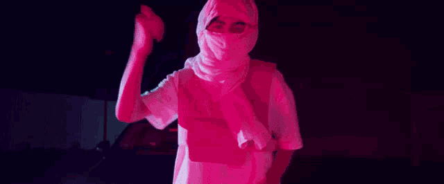 a person wearing a white hoodie and a pink mask is standing in front of a car at night .