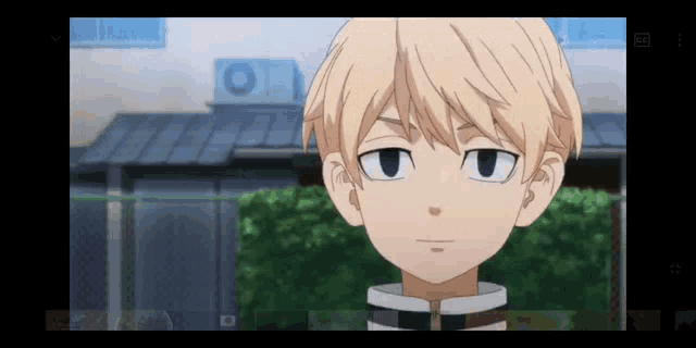 a young boy with blonde hair is standing in front of a building and looking at the camera .