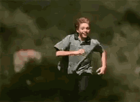 a young boy is running in the woods with the word ritorno written on the ground .