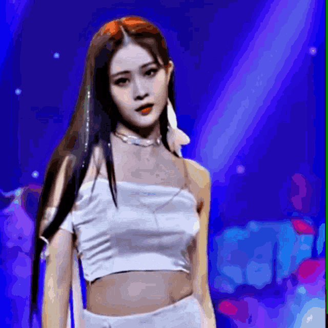 a woman in a white crop top and white shorts is standing in front of a blue background