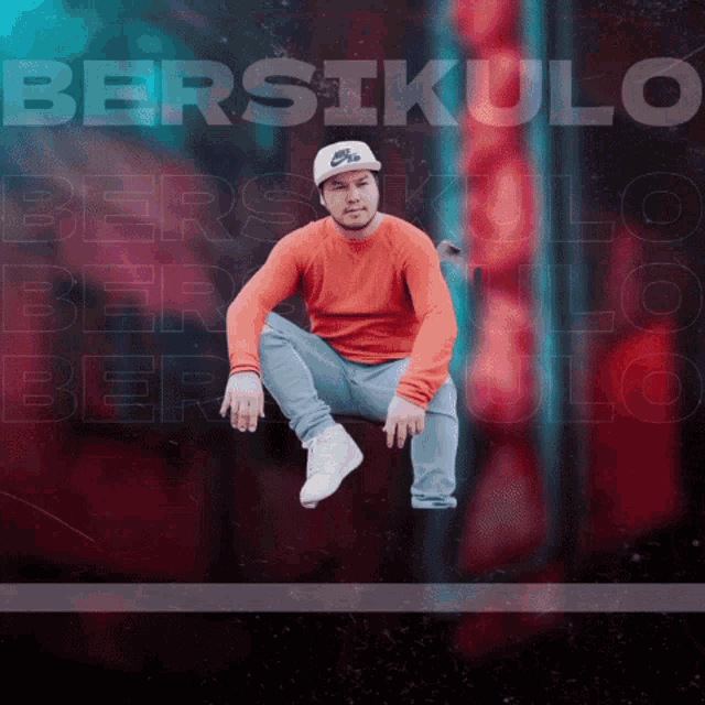 a man wearing an orange sweater and a white nike hat sits in front of a poster that says bersikulo