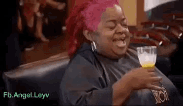a woman with pink hair is holding a glass of orange juice .