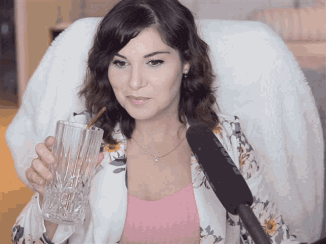 a woman holds a glass with a straw in her hand